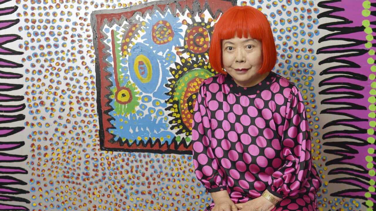 A portrait of Yayoi Kusama, wearing a black dress with pink dots.
