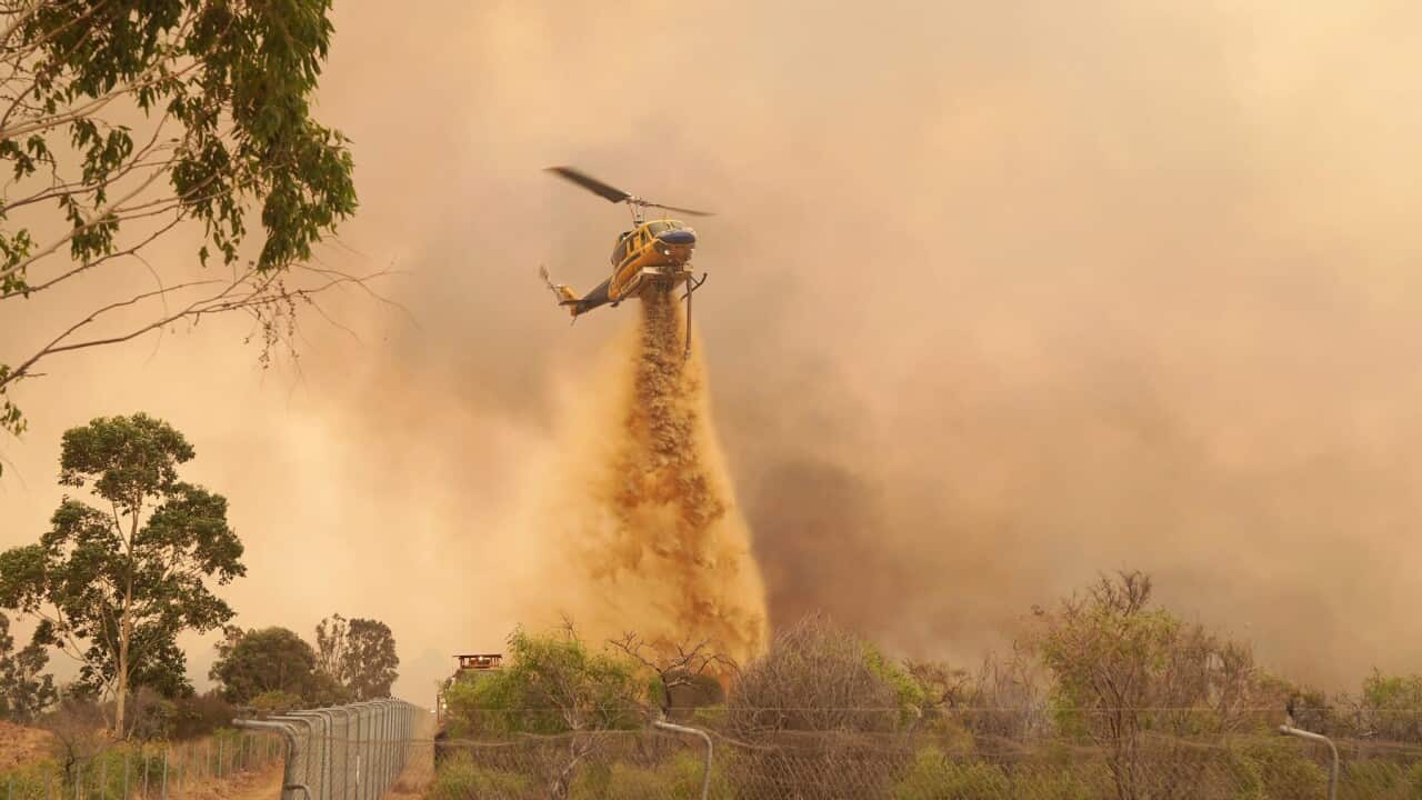 1. A helicopter drops fire retardant on a fire near Wooroloo.