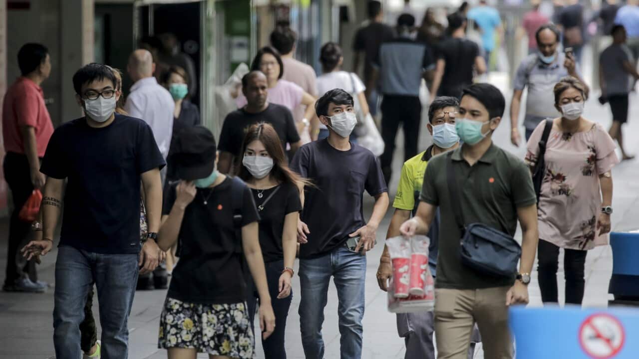 People, wearing face masks, walk past a shopping mall in Singapore, 7 April 2020.