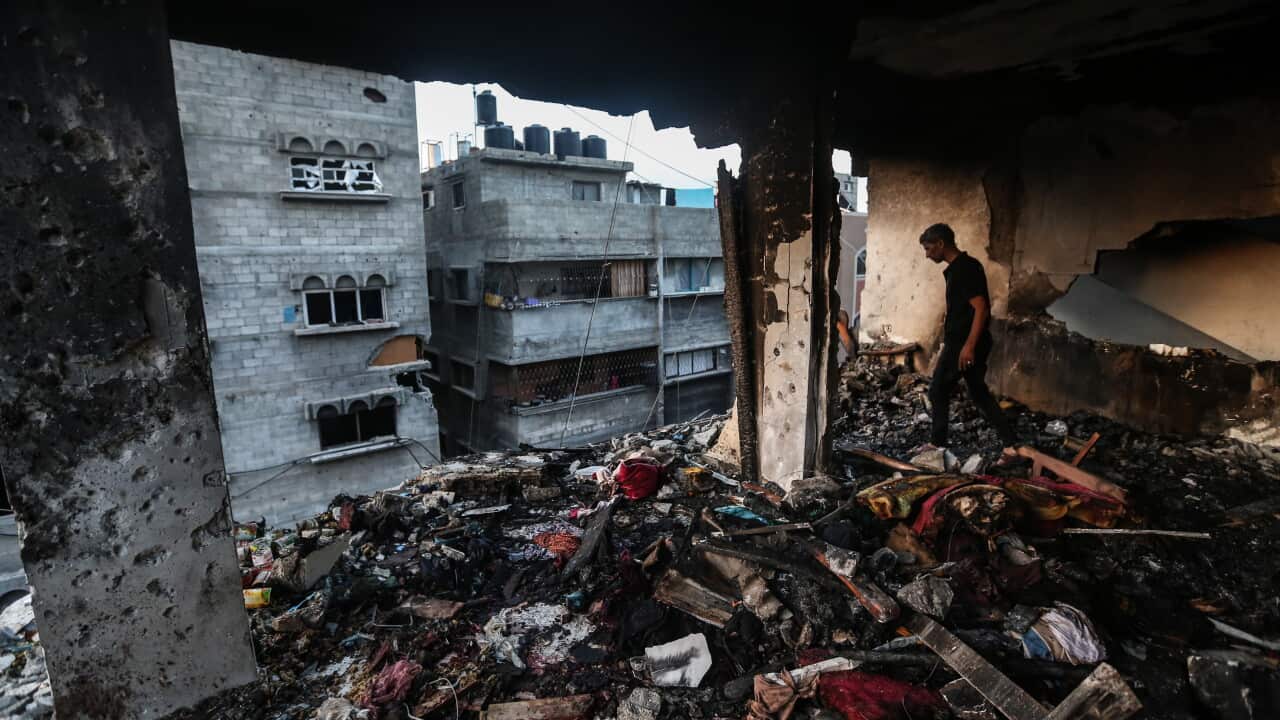 A man stands inside a bombed out building, looking down from a high story.