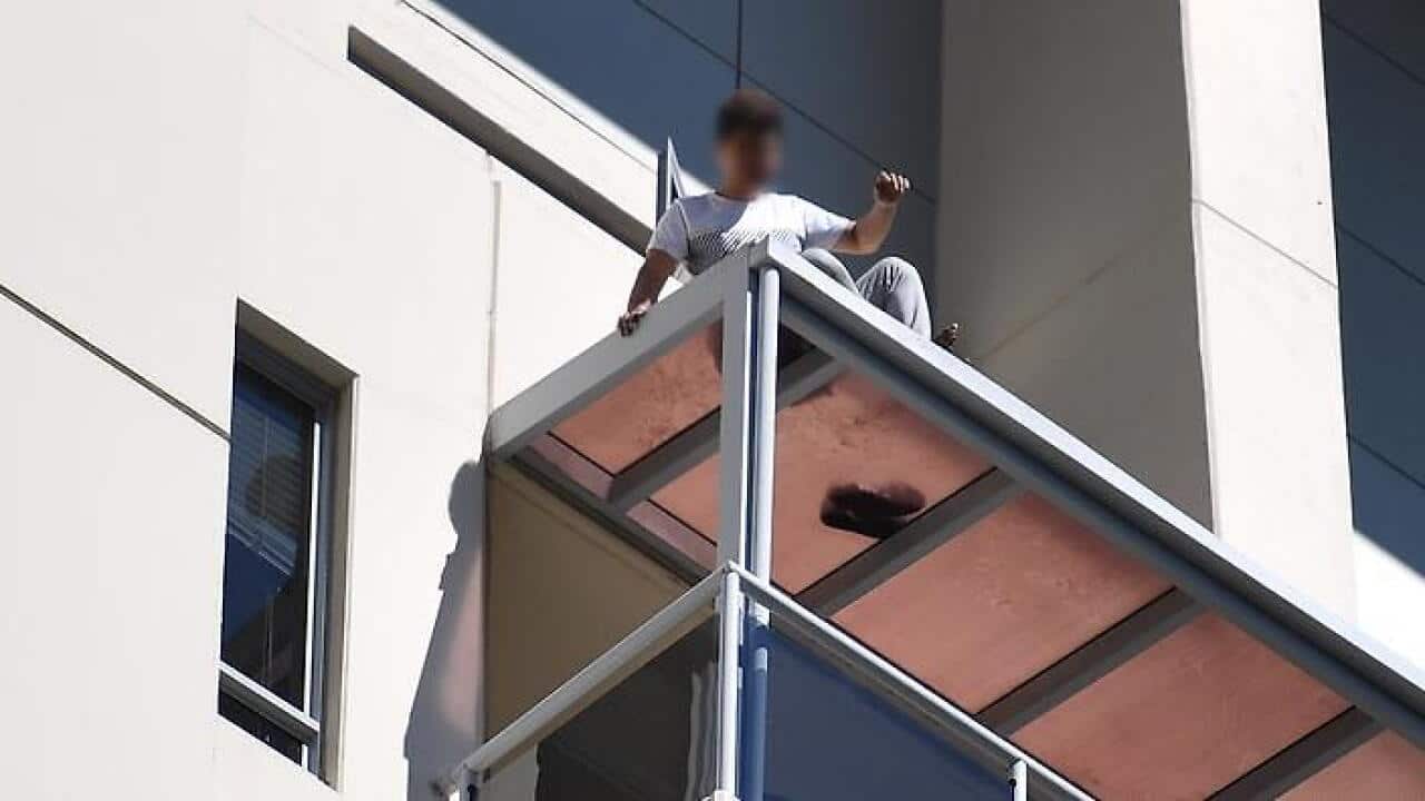 A man is seen on a ledge on an apartment building in Chatswood, Sydney, Monday, October 9, 2017.