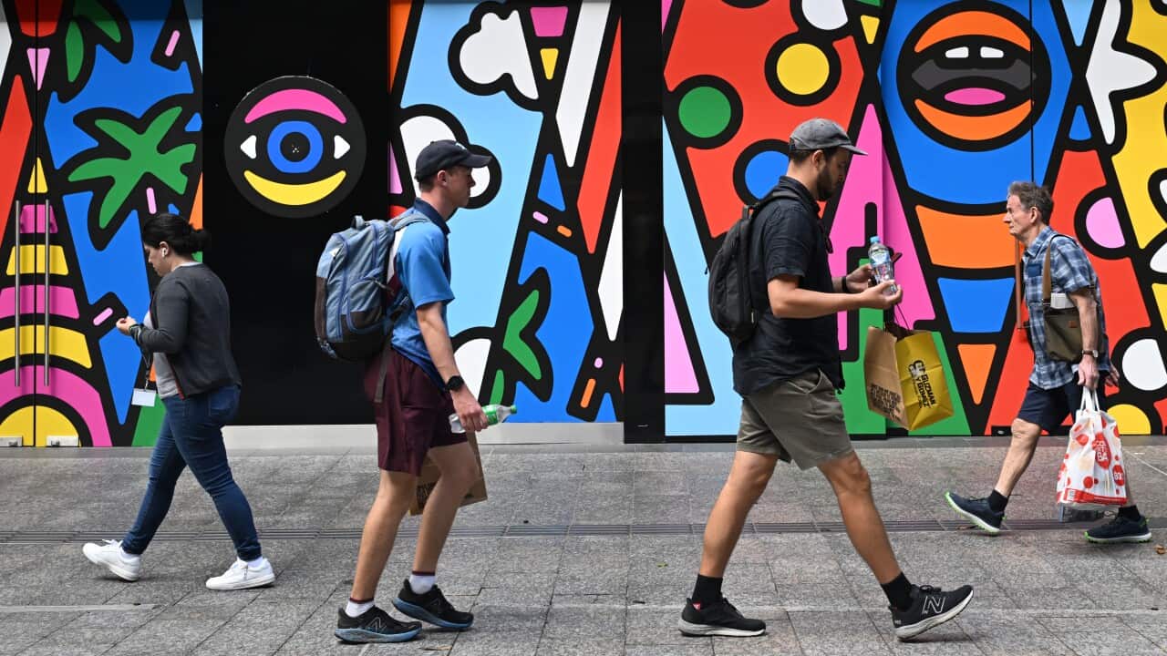 Four people walking past a mural in Brisbane.