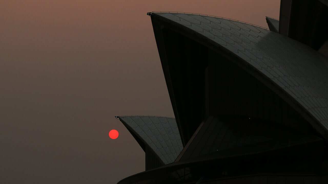 The sun is seen through bushfire haze next to the Sydney Opera House as Sydney suffers through hot weather.