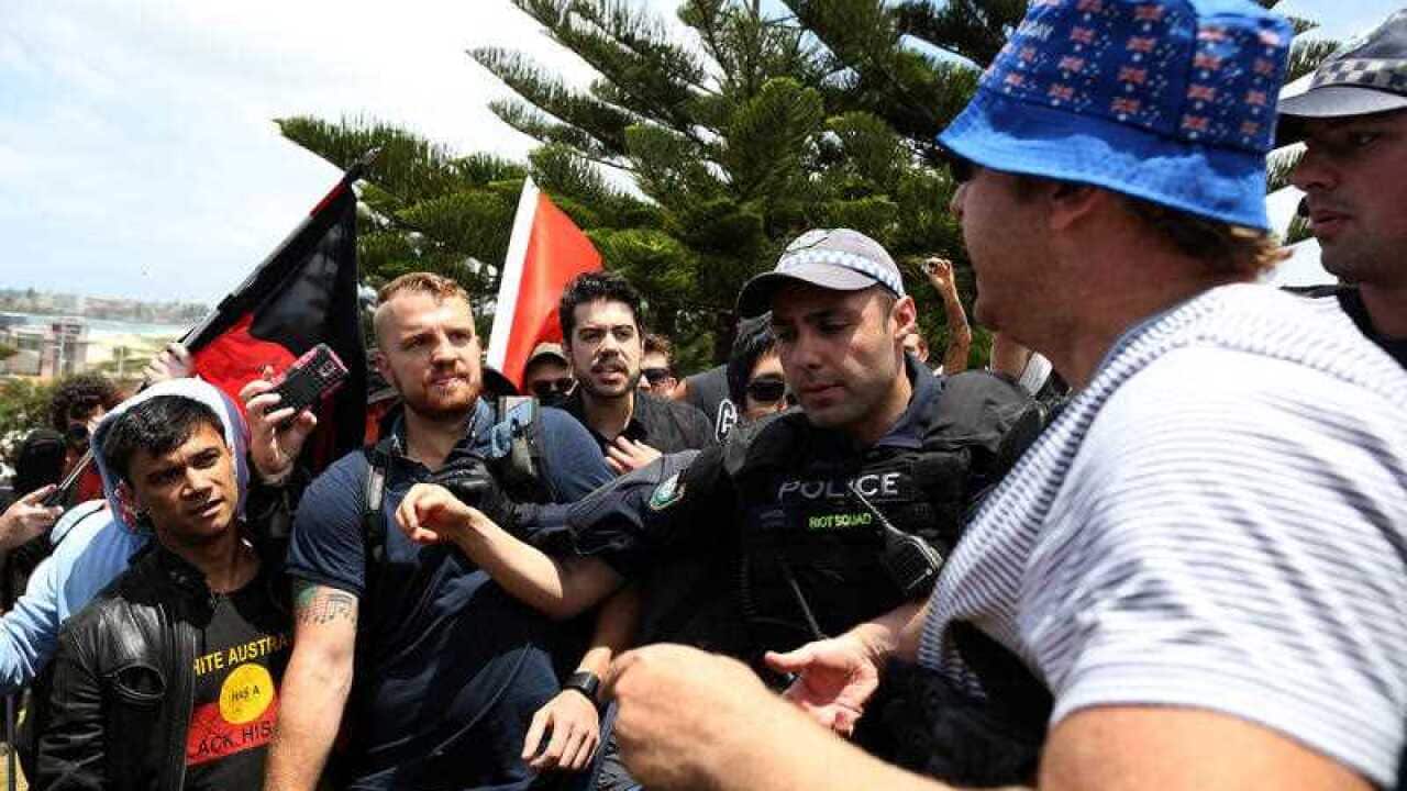 A man is confronted by protesters during an event against the 10th anniversary of the Cronulla riots rally, at the Don Lucas reserve in Cronulla