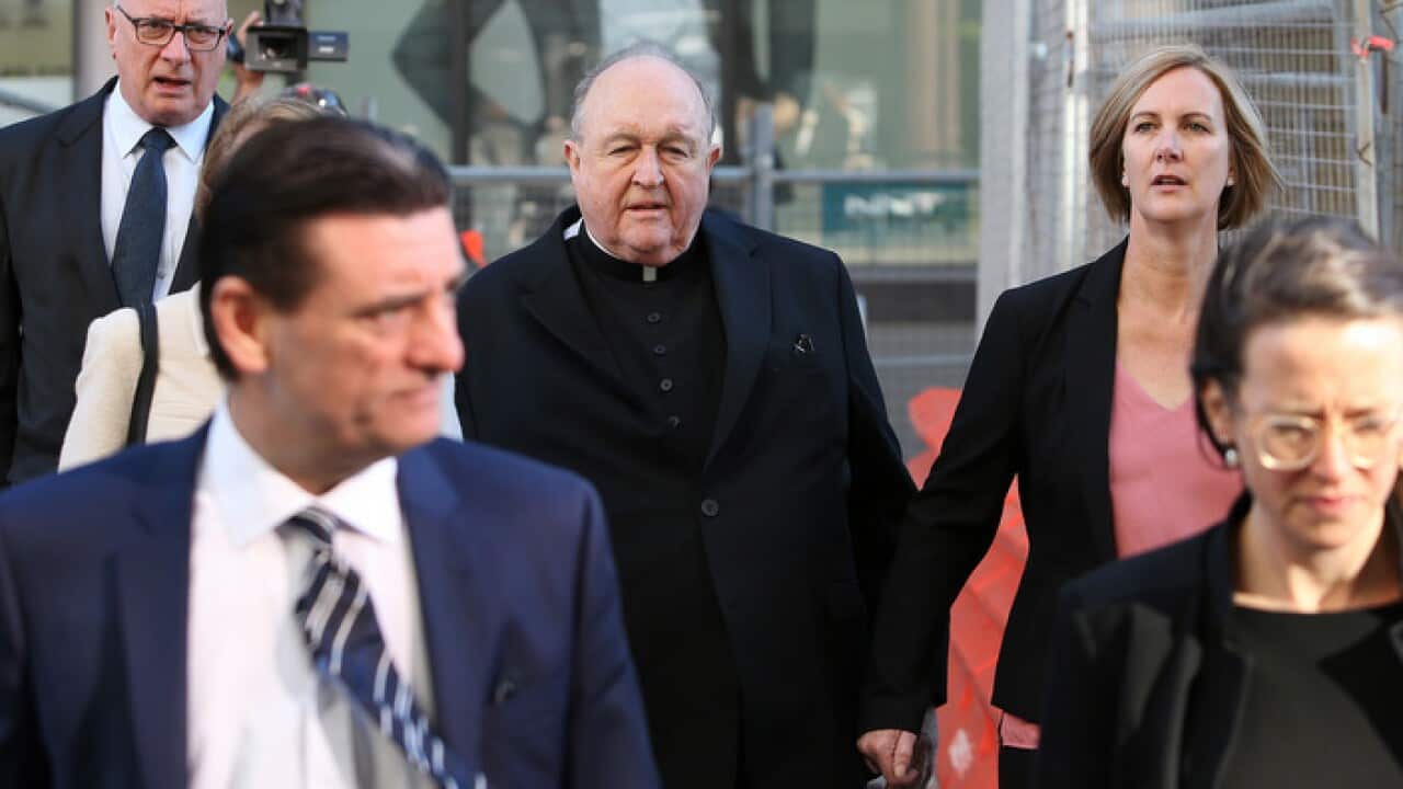 Archbishop Philip Wilson (centre) arrives at Newcastle Local Court