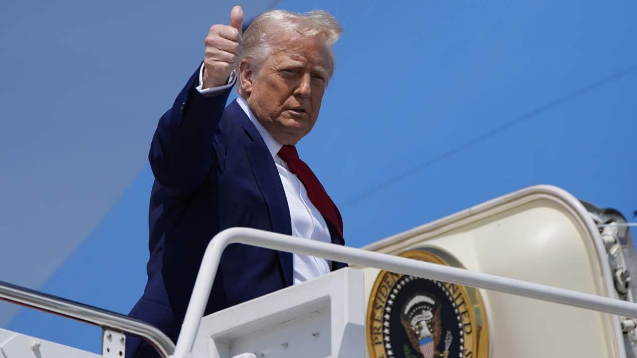 Donald Trump, in a blue suit, gives a thumbs-up gesture as he boards Air Force One.