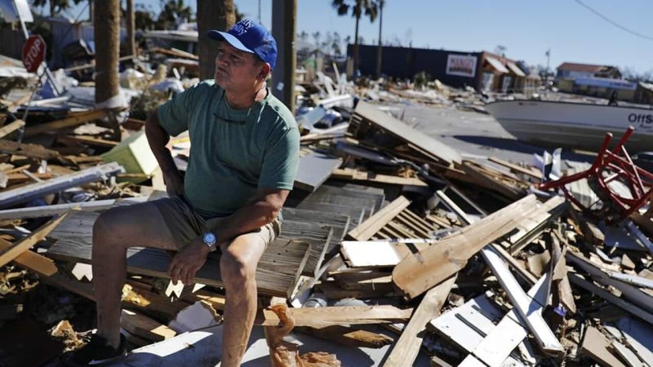 Hector Morales sits on a debris pile near his home which was destroyed