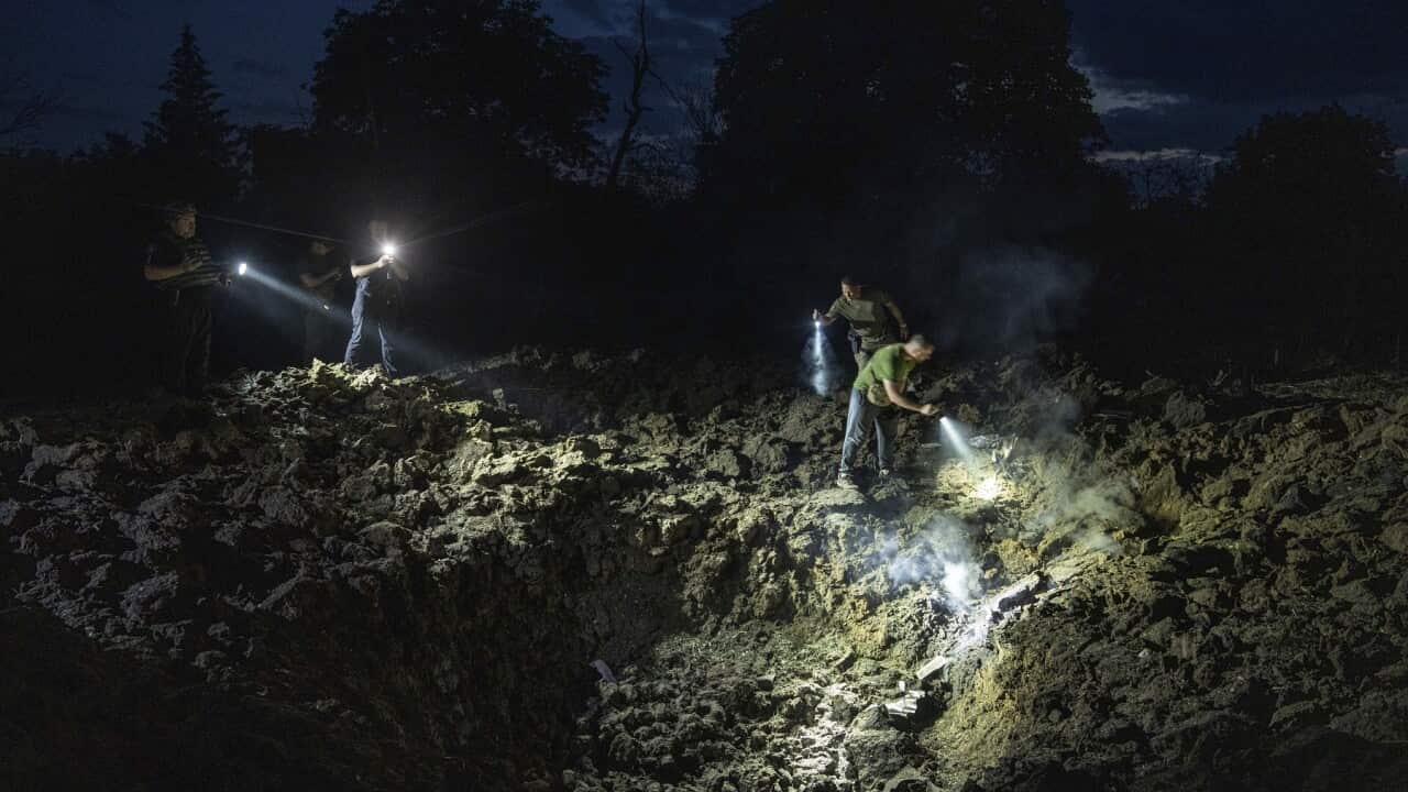 Ukrainian policemen looking for fragments of a rocket in a crater after a Russian attack on Pokrovsk, Ukraine