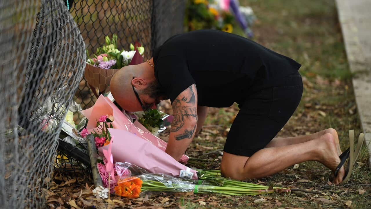 A man pauses near flowers placed at the scene where seven children where hit on a footpath