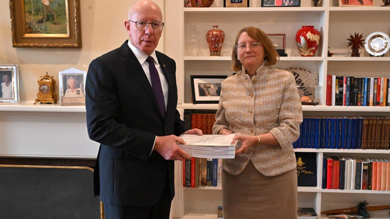 A woman hands a document to a man.