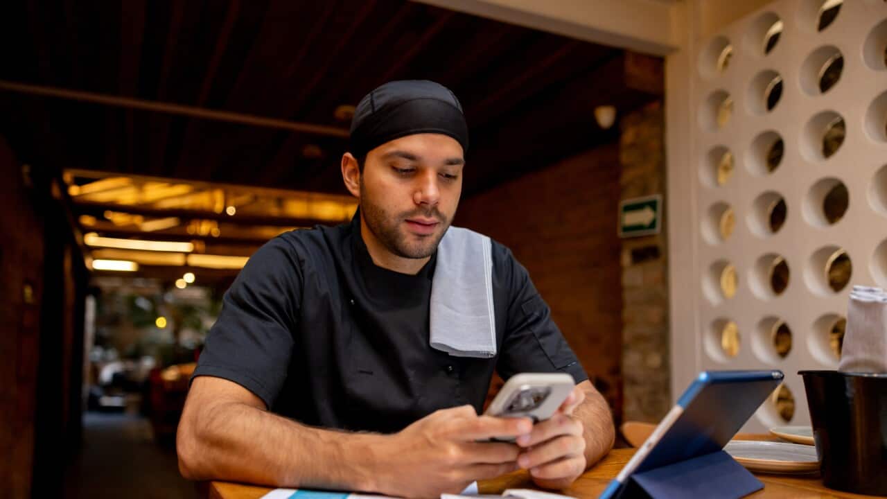 Chef doing the books at a restaurant and using an app on his cell phone