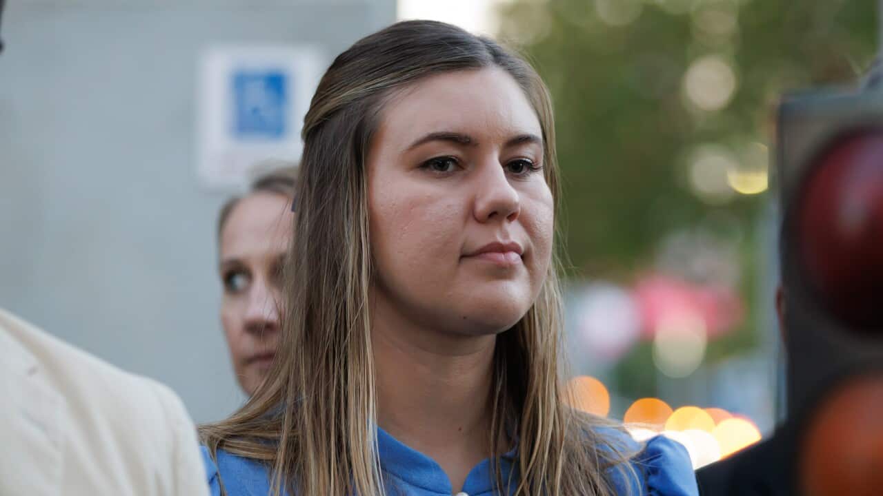 A woman in a blue dress and blonde hair looks on.