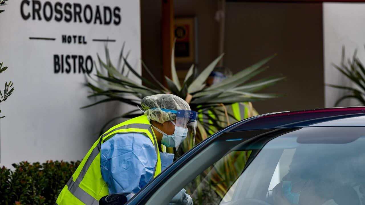 NSW Health workers dressed in Personal Protective Equipment administer COVID-19 tests to people in their cars at the Crossroads Hotel testing centre in Sydney.