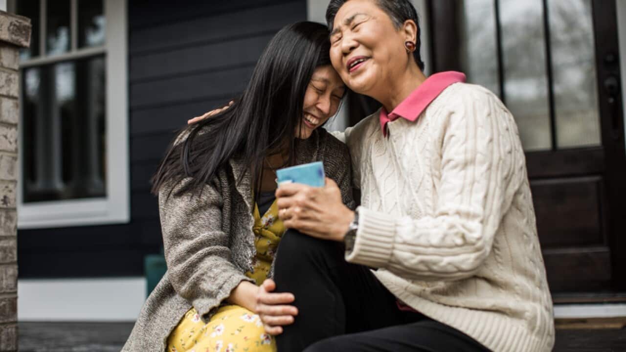 Adult woman and senior mother talking on front porch