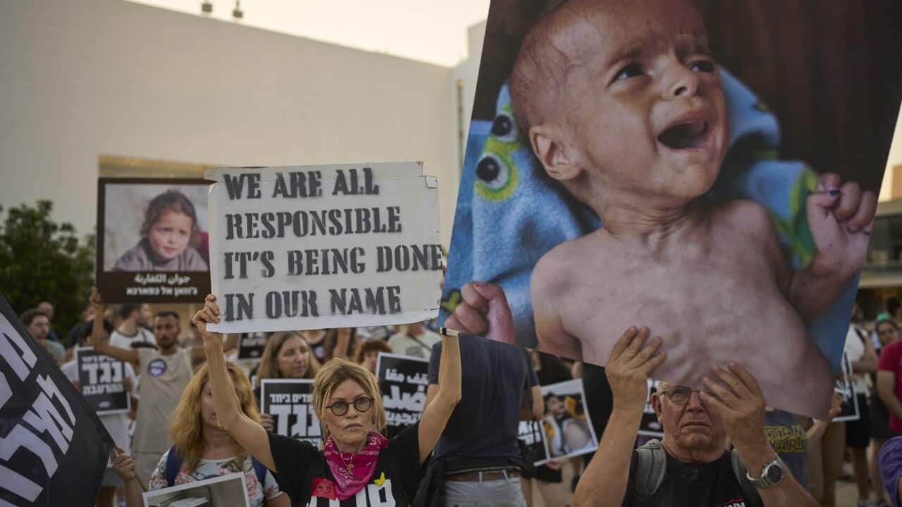 Protesters march with image of starving child and signs reading 'WE ARE ALL RESPONSIBLE IT'S BEING DONE IN OUR NAME"