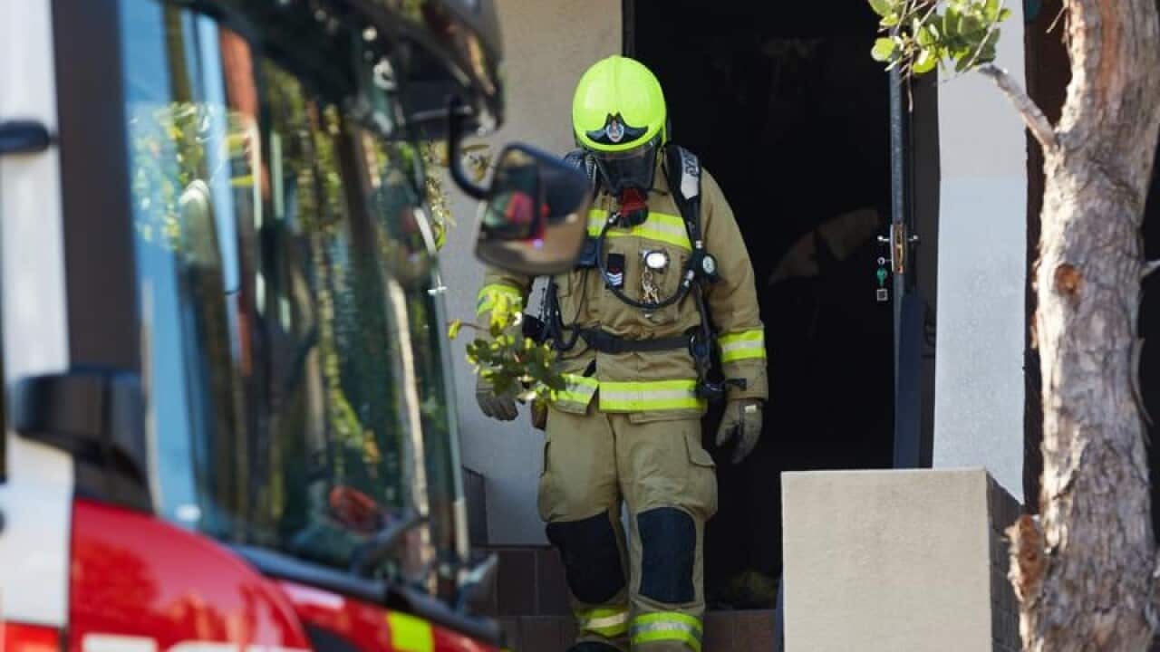 Fire crew works outside the scene of a fatal house fire.