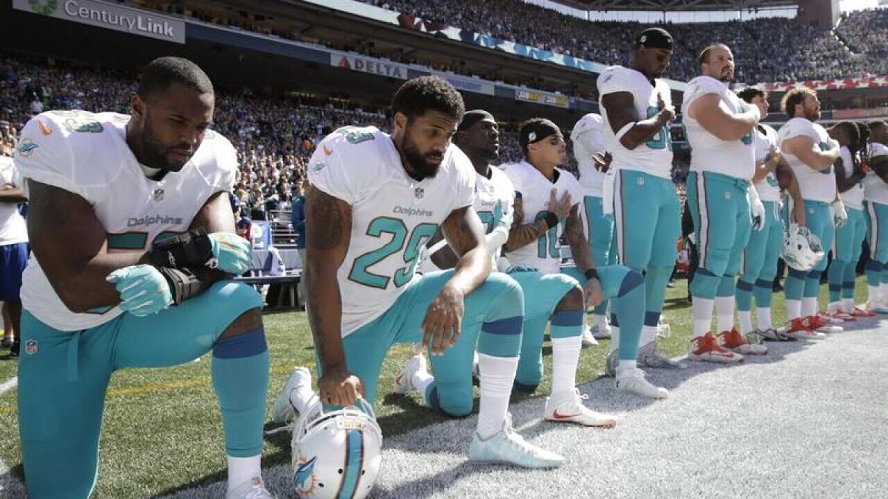 Miami players kneel during the national anthem.