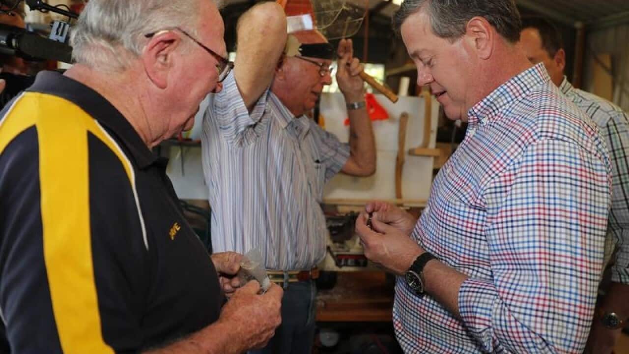 LNP leader Tim Nicholls checks a pen made by a Mens Shed member.