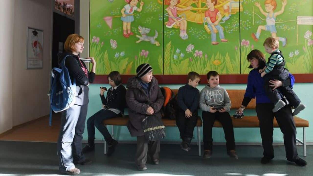 Children wait in a queue for vaccination against measles in Kiev
