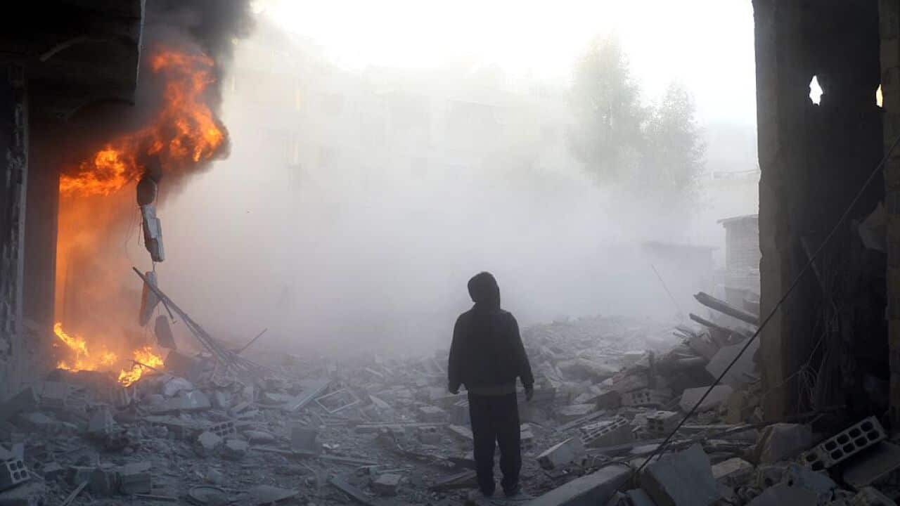 A man walks near a building on fire following a reported air strike in the rebel-held region of Eastern Ghouta