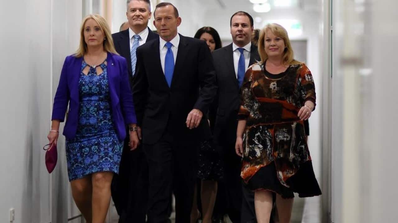 Prime Minister Tony Abbott arrives surrounded by fellow MPs.