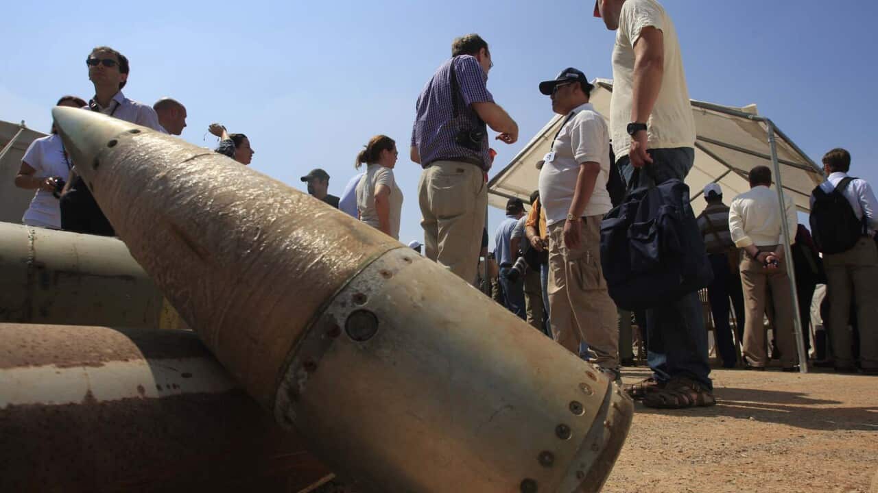 People stand near cluster bomb units.