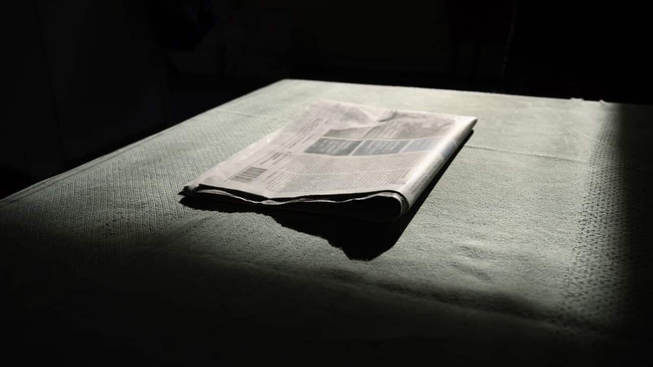 A newspaper folded, waiting to be read in morning light, low key