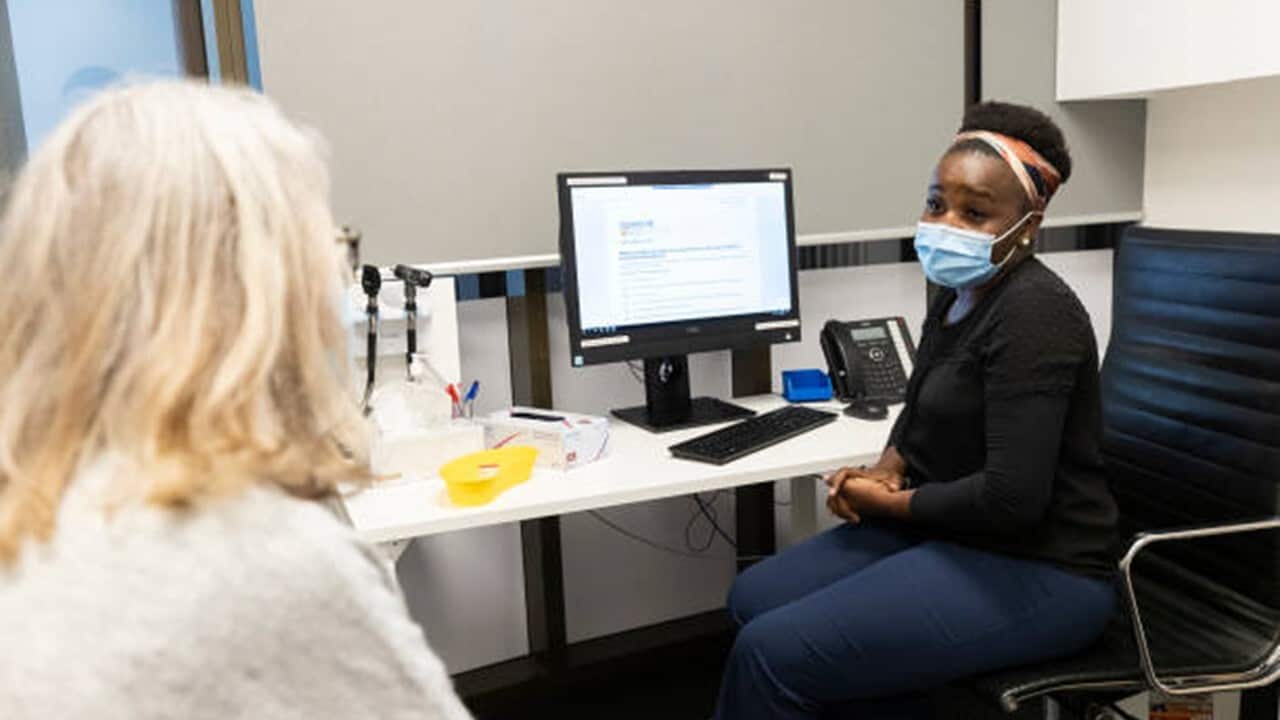 Nurse Emeldah Mufara speaks to Margaret Donnellan before administering the AstraZeneca vaccine at the Sydney West COVID Vaccine Centre.jpg