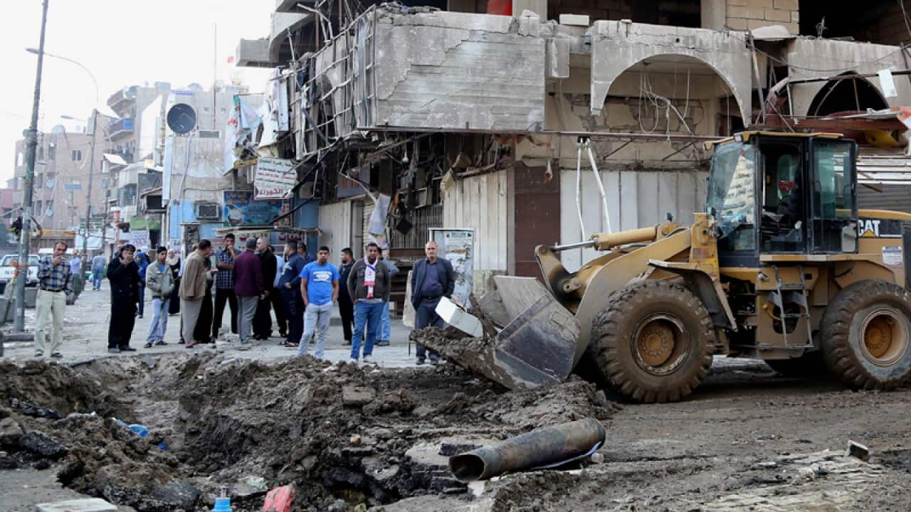 Civilians clear the aftermath of a car bomb in Baghdad