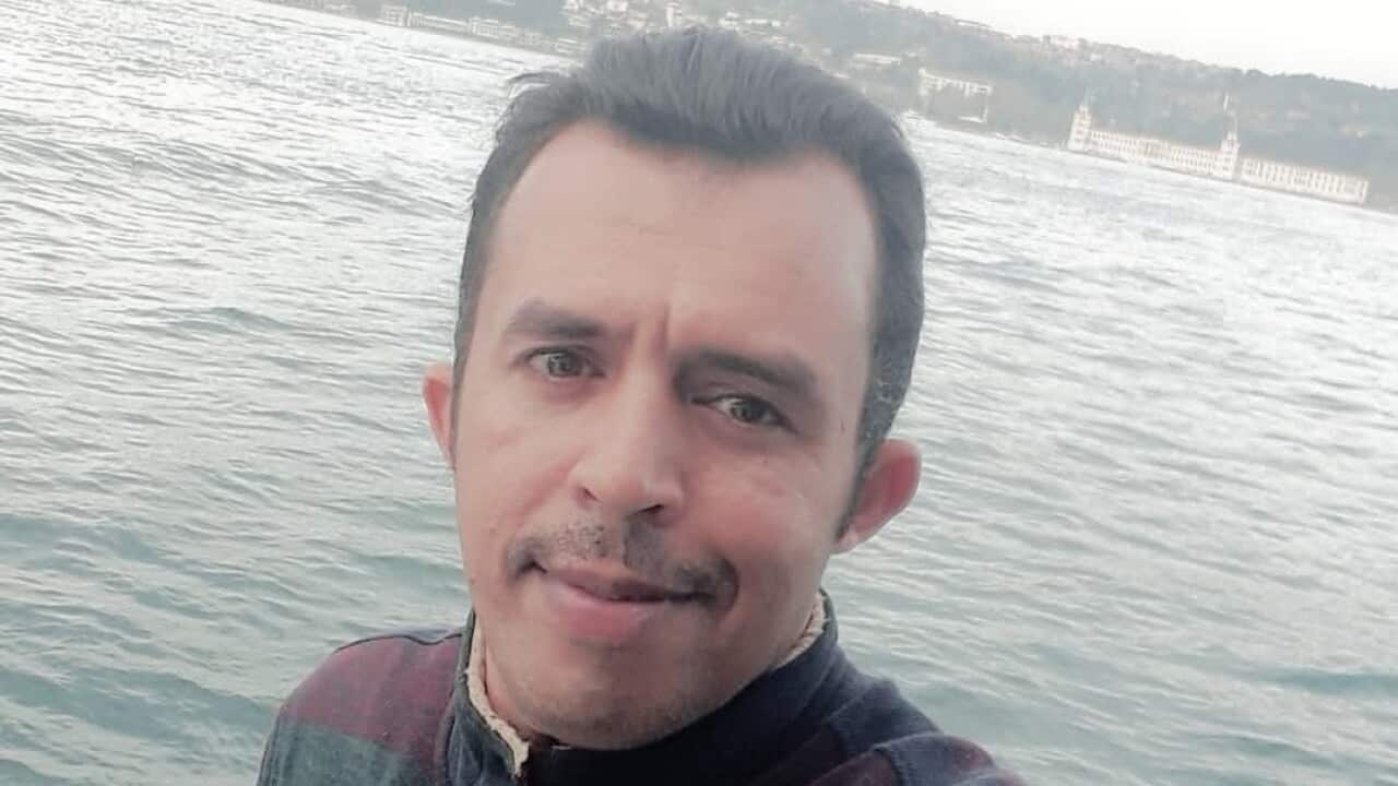 A man in a red blue and green striped jacket taking a selfie