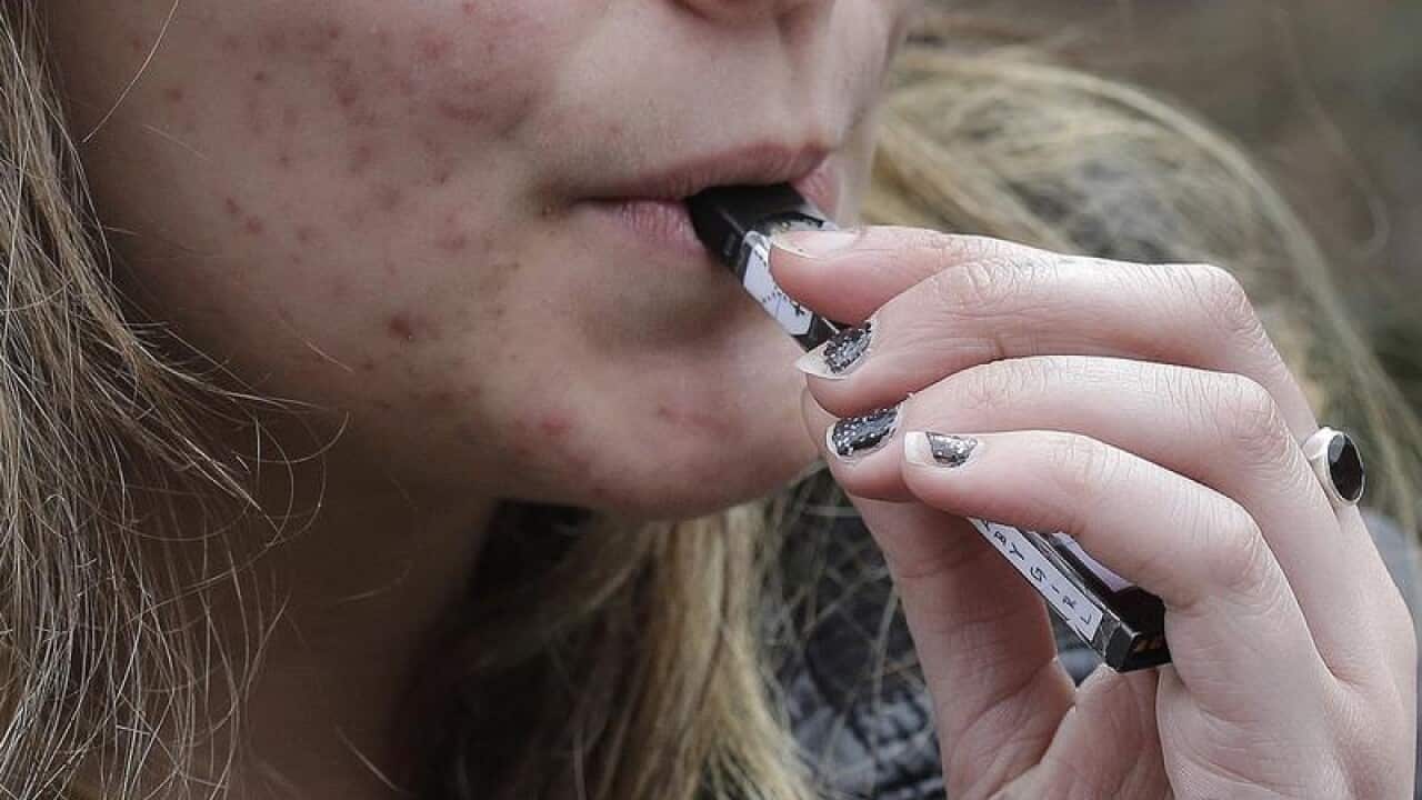 A high school student uses a vaping device.