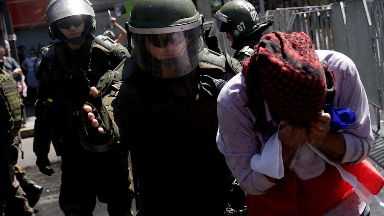 A policeman escorts an injured protester on the sixth day of protests against the Government, in Santiago, Chile.