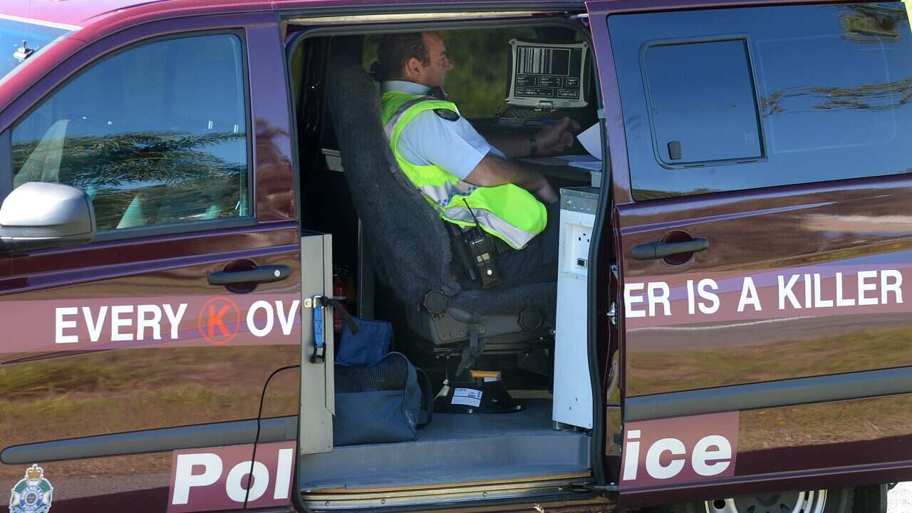 A police officer operates a mobile speed camera from the back of a van on the Pacific Highway on the Gold Coast, Thursday, June 21, 2012. (AAP Image/Dave Hunt) NO ARCHIVING