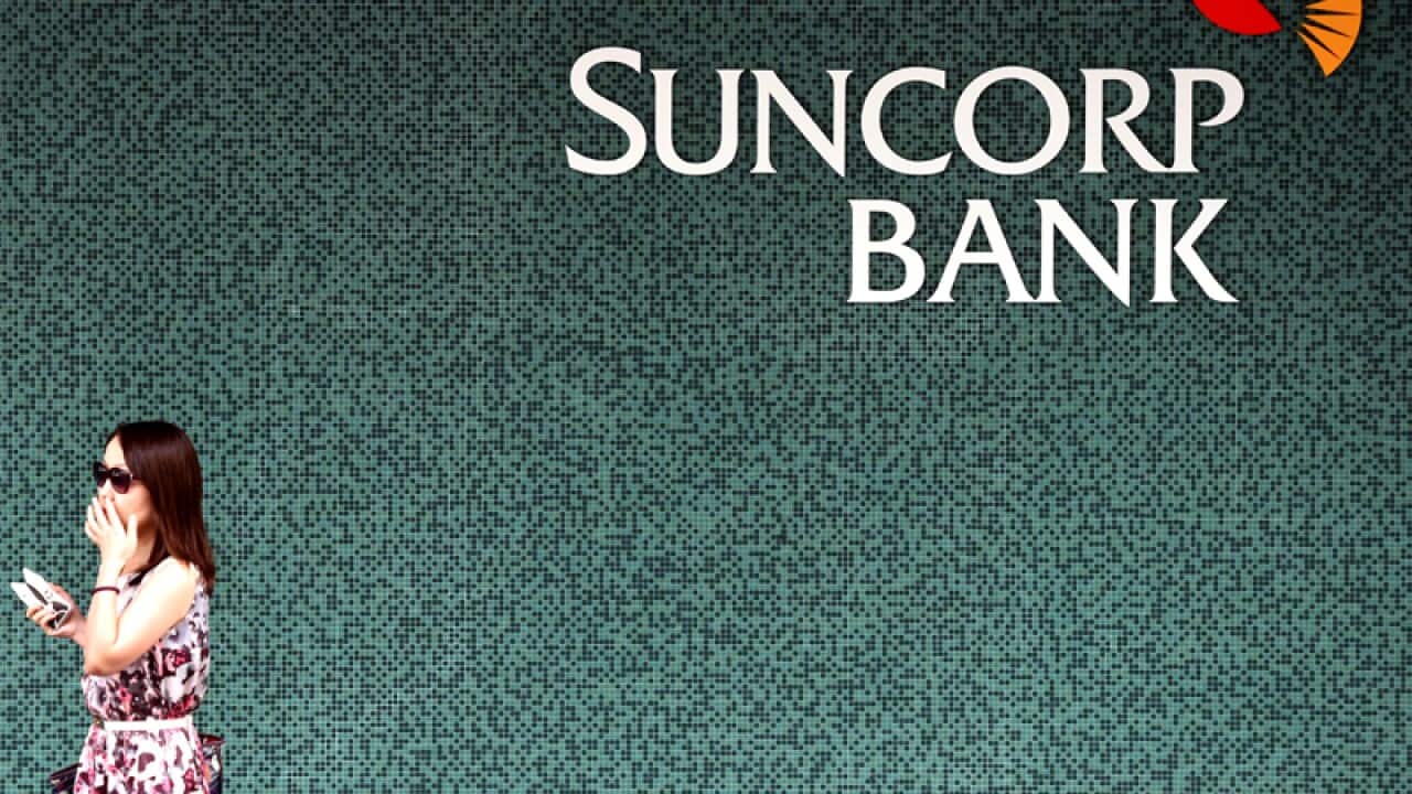 A woman walks past a Suncorp Bank