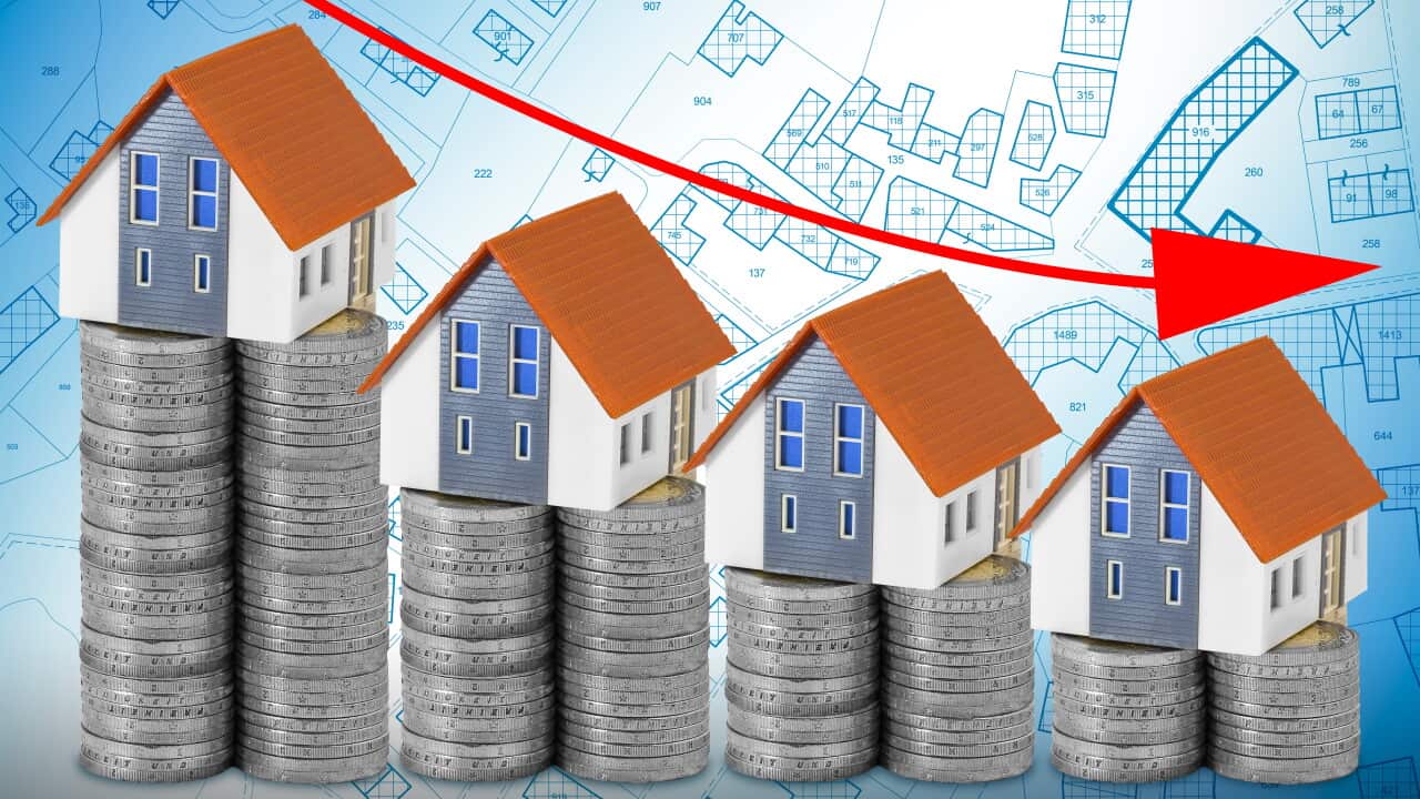 A GROUP OF SMALL MODEL HOUSES PLACED ON DESCENDING STACKS OF COINS WITH A DOWNWARD ARROW symbolizing financial decline and real estate depreciation. Ideal for finance and housing concepts