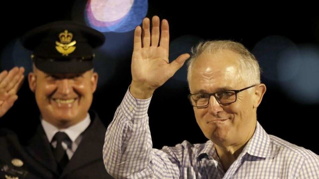 Prime Minister Malcolm Turnbull waves as he boards a plane