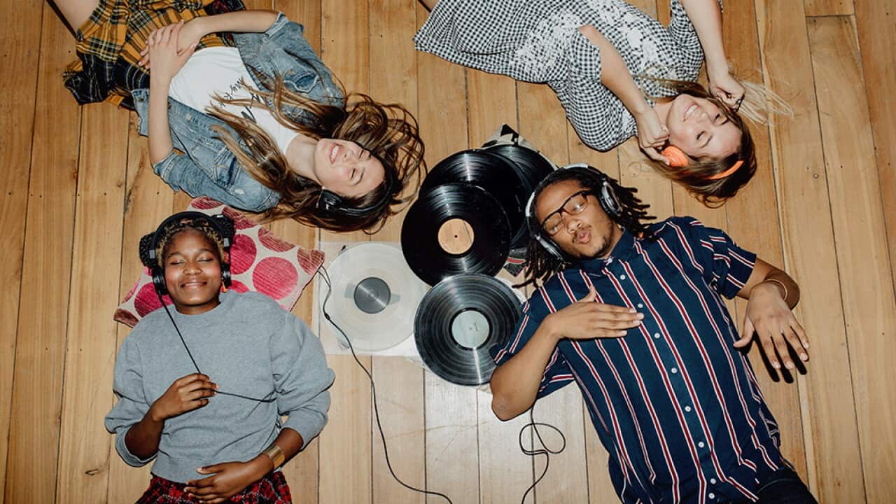 Group of young friends listening to music with vinyls scattered about