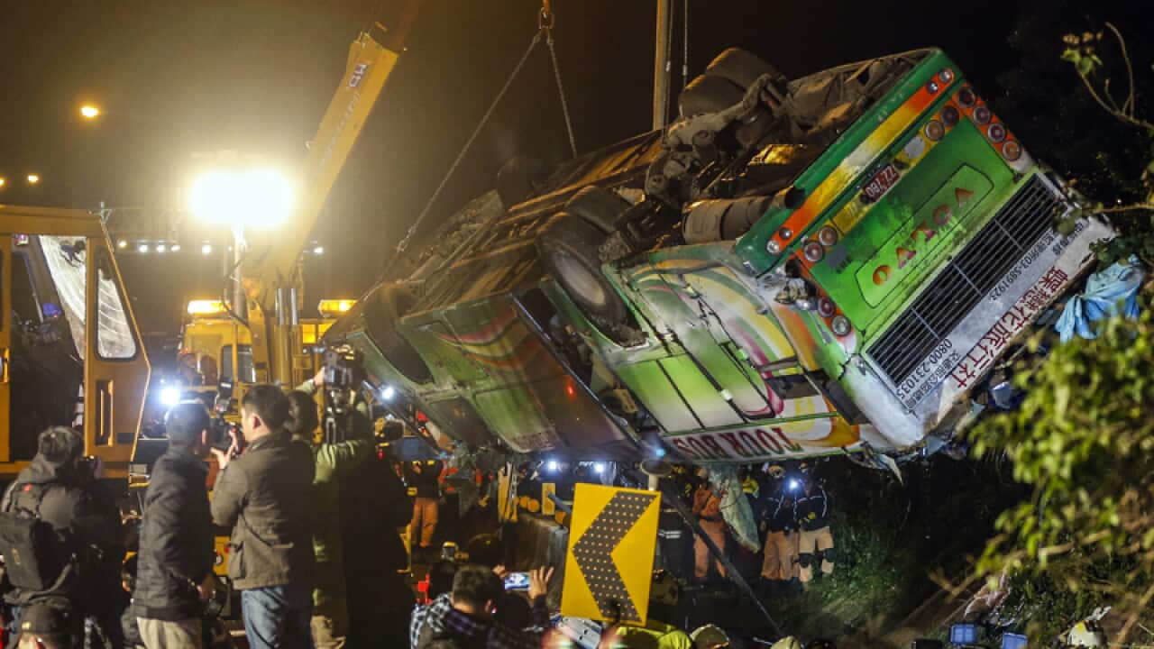 A crane lifts the wreck of a bus that crashed at a highway in Taipei
