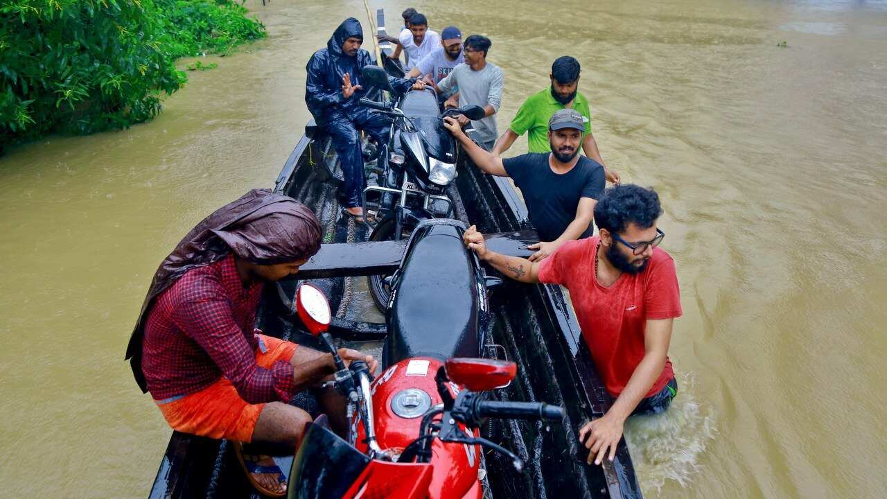 People salvage motorcycles in a country boat in a flooded area at Kainakary in Alappuzha district, Kerala state.