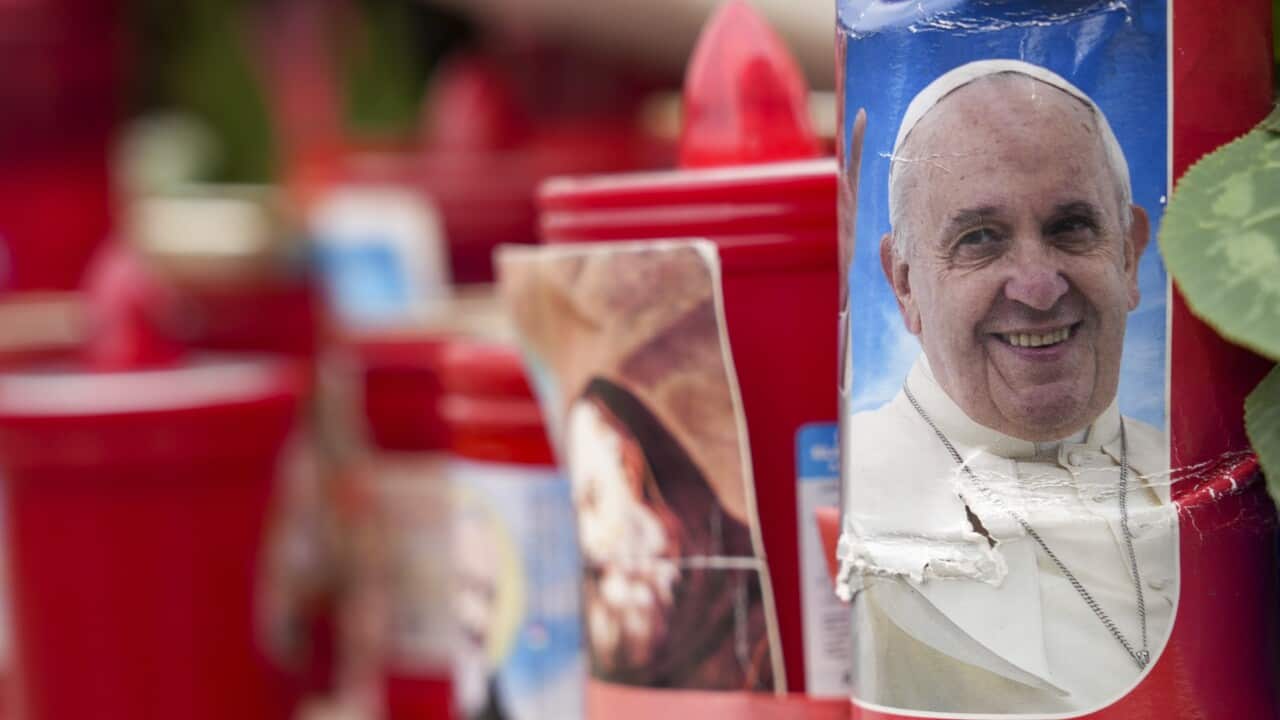 A candle with a portrait of Pope Francis is seen in front of a hospital