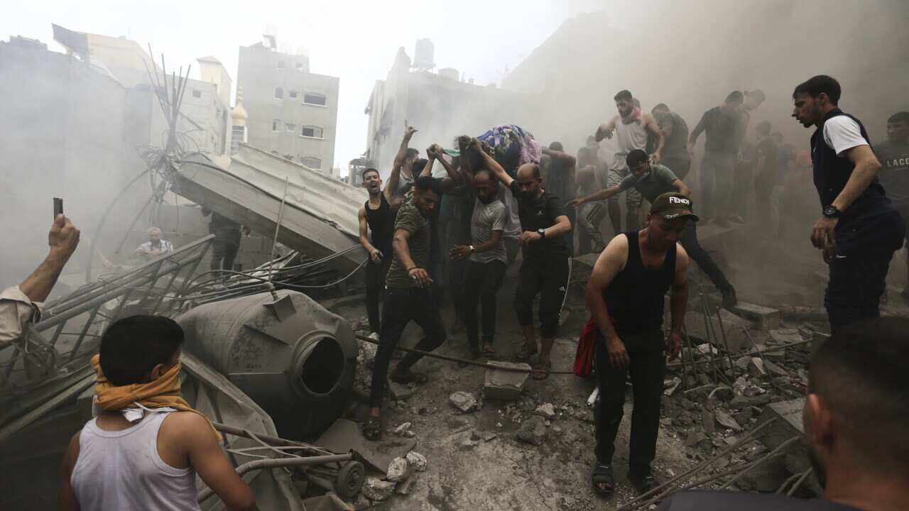 Palestinians remove a dead body from the rubble of a building after an Israeli airstrike