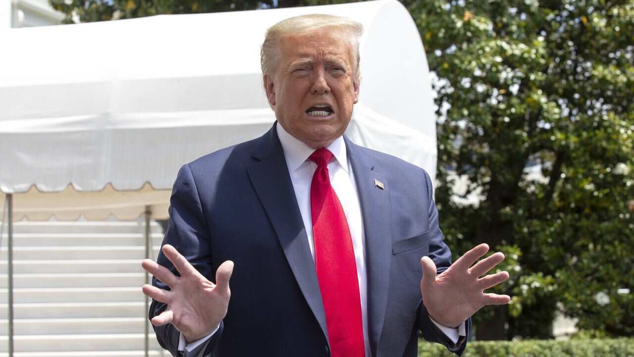 US President Donald Trump speaks to members of the media as he departs the White House in Washington.