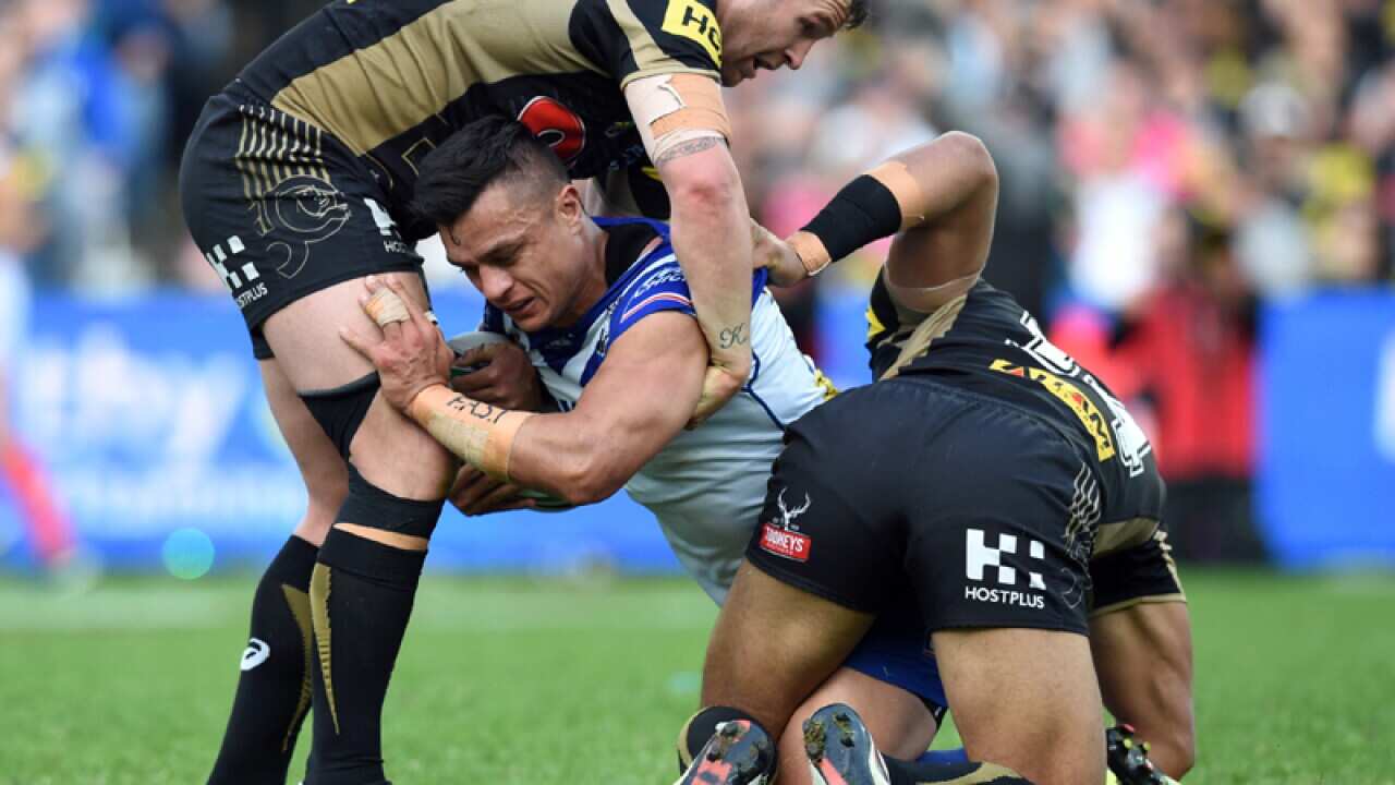 Sam Perrett (C) of the Bulldogs is tackled by Penrith players