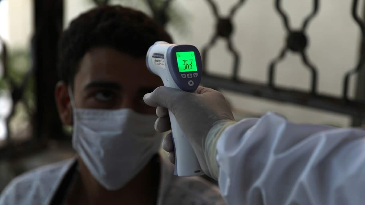 A nurse checks the body temprature of a possible COVID-19 patient at the community treatment center in Ariha city, south Idlib, Syria, 25 August 2020