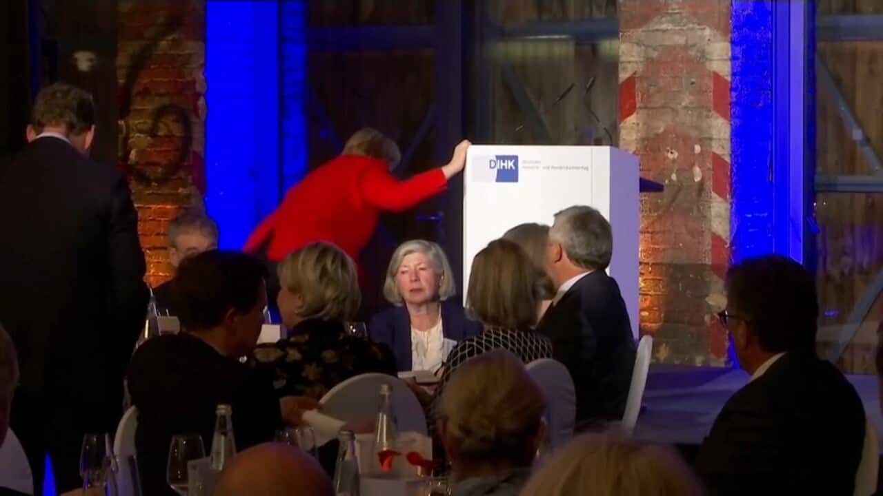 German Chancellor Angela Merkel stumbles as she makes her way on stage. 