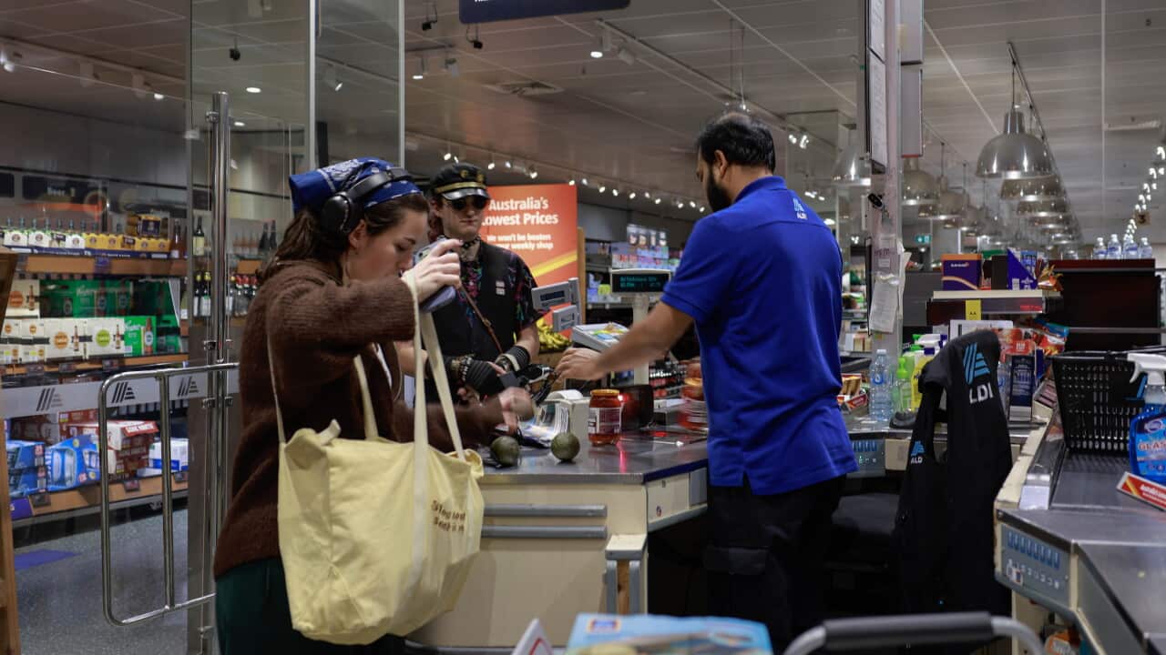 A cashier serves customers at a supermarket in Canberra