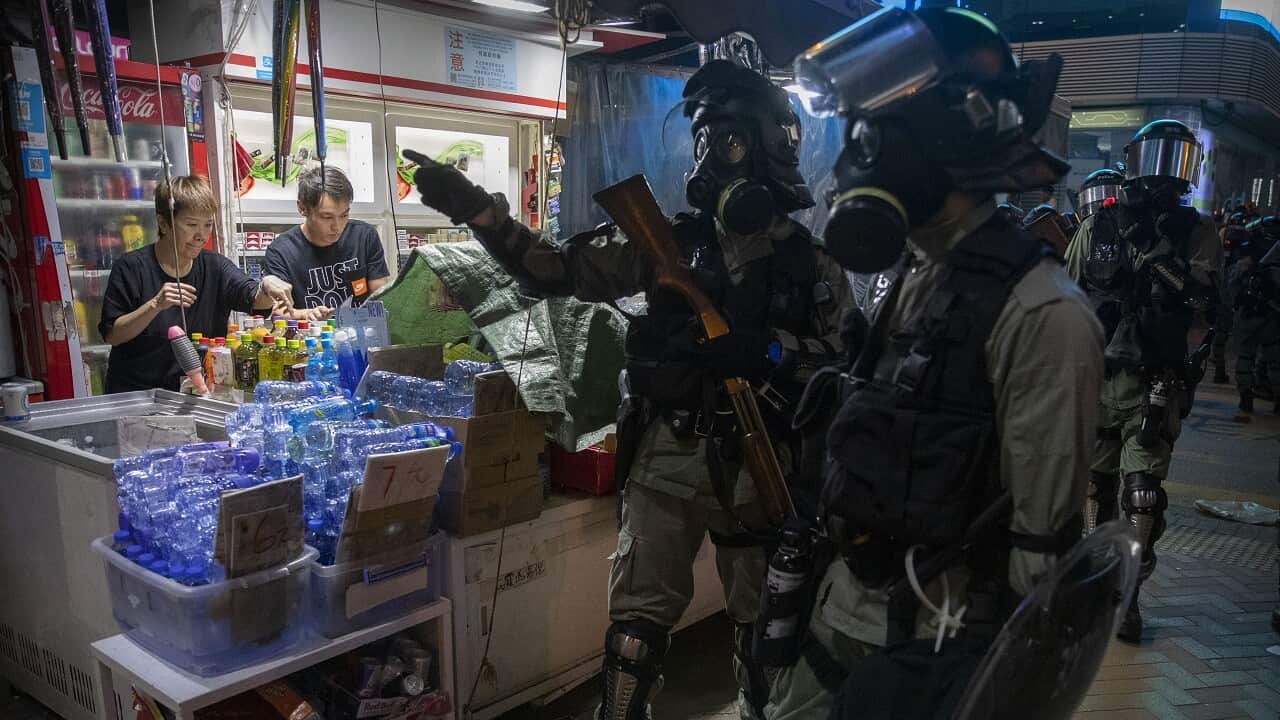 Riot police gather as street vendors work in Hong Kong.