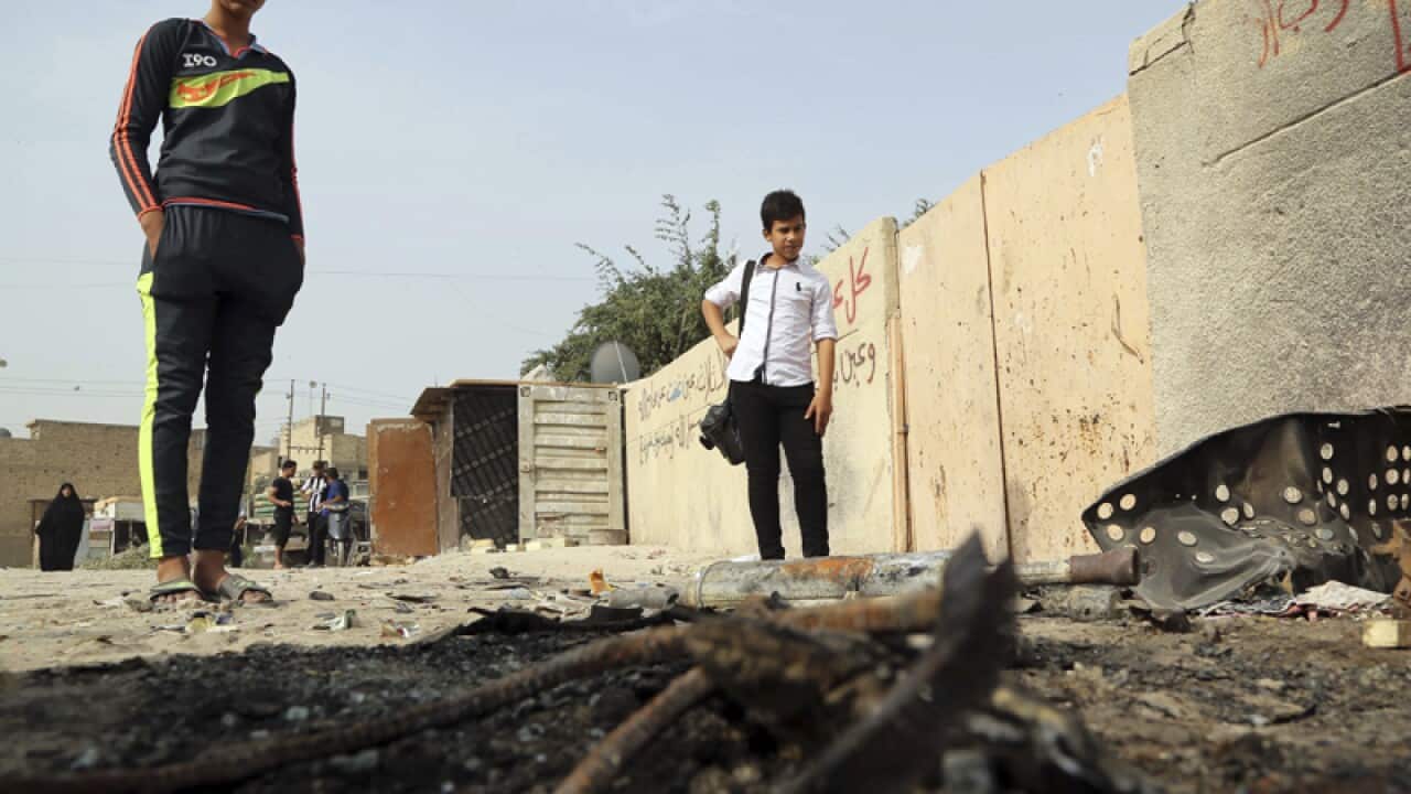 People inspect the aftermath of a car bomb explosion in Hurriyah