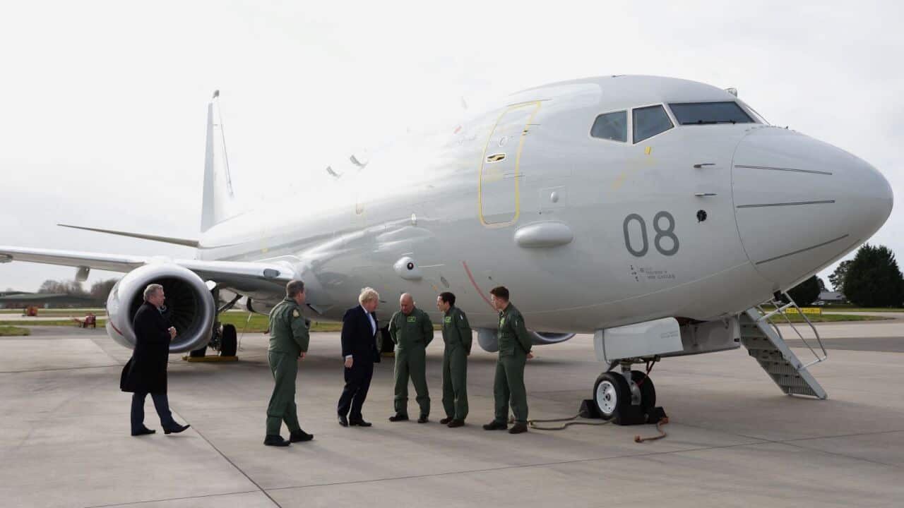 Prime Minister Boris Johnson standing next to a RAF P-8A Poseidon plane