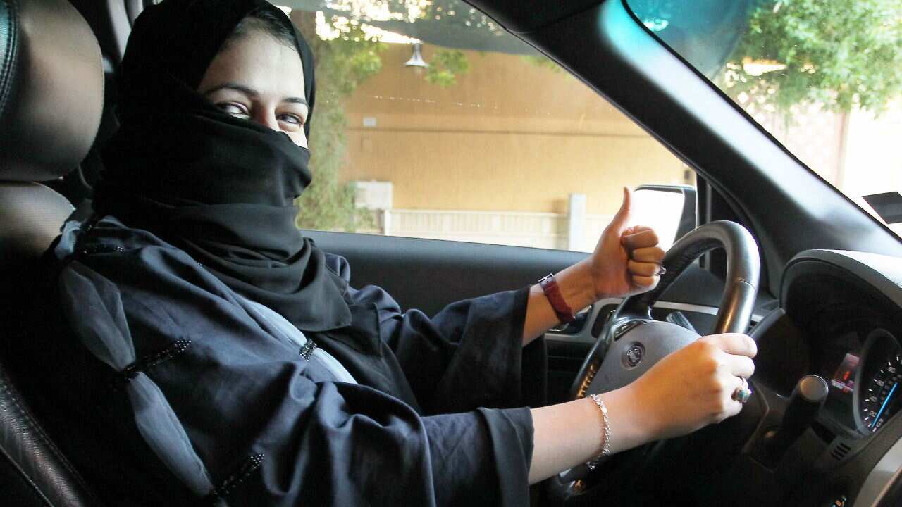 A woman gives a thumb up as she sits behind the wheel of a car in Riyadh, Saudi Arabia.